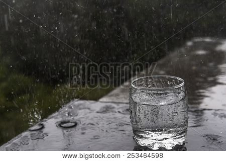 Great Conceptual Image With A Glass Of Water, Forgot Outside, In The Summer Rain, With Water Droplet