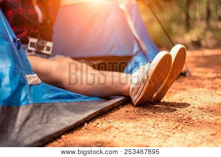 Close Up Of Woman Strecthing Feet With Shoe With Nature Background. Tourist Woman Resting In Camping
