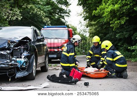 Firefighters Helping A Young Injured Woman After A Car Accident.