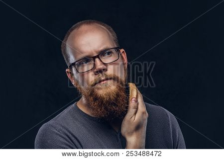 Close Up Portrait Of A Redhead Bearded Male Wearing Glasses Dressed In A Gray T-shirt, Cares About H