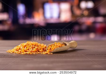 Lot Of Whole Raw Red Lentils With Wooden Scoop With Restaurant In Background