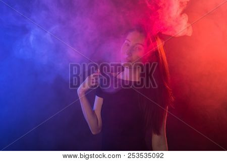 Portrait Of Asian Woman Smoking Vape Or E-cigarette In Neon Light At Black Background.