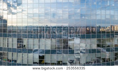 The reflection of cityscape in the windows of modern business center building in the summer day, at sunset.