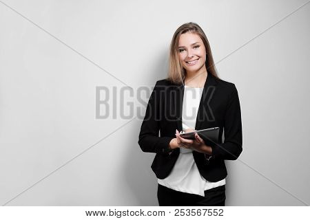Portrait Of A Beautiful Smiling Woman Blonde With A Tablet In Her Hands In A Business Suit And Jacke