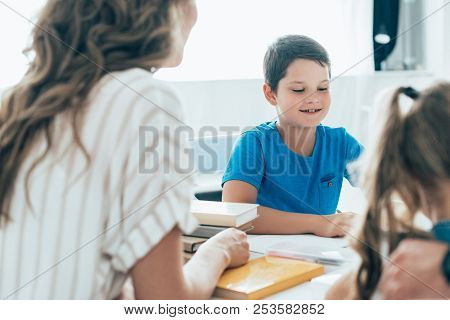 Partial View Of Mother And Kids Doing Homework Together At Home