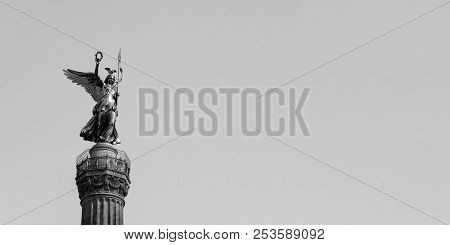 The Golden Statue Of Victoria On Top Of The Victory Column In Berlin, Germany Against A Blue Sky Wit
