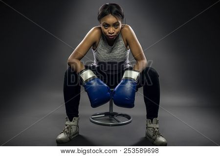 Black Female Wearing Boxing Gloves Looking Angry As A Boxer, Mma Fighter Or Self Defense Trainer Sit