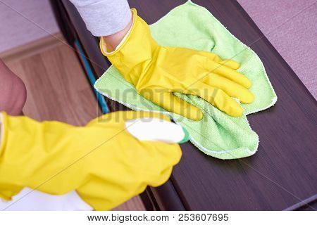 A Picture Of Hands In Yellow Gloves Cleaning The Wooden Surface