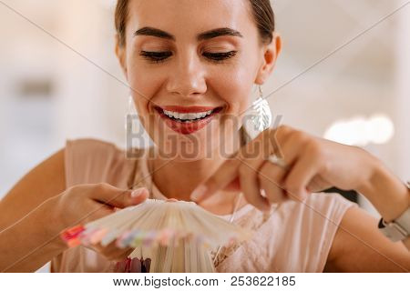 Beautiful Woman Wearing Nice Earrings Looking At Nail Polish Colors
