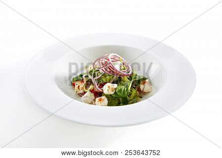 Green Salad with Goat Cheese, Spinach, Tomato and Red Onion Rings Isolated on White Background. Restaurant Starter Menu with fresh Spinacia and Chard Leaves, Tomatoes, Greens, Spices Close Up