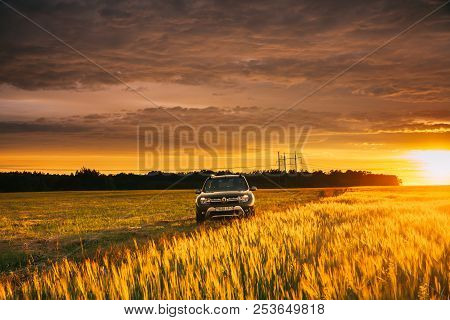 Renault Duster Or Dacia Duster Suv In Road Through Summer Wheat Field In Amazing Sunset Time.