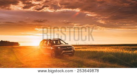 Renault Duster Or Dacia Duster Suv In Road Through Summer Wheat Field In Amazing Sunset Time.