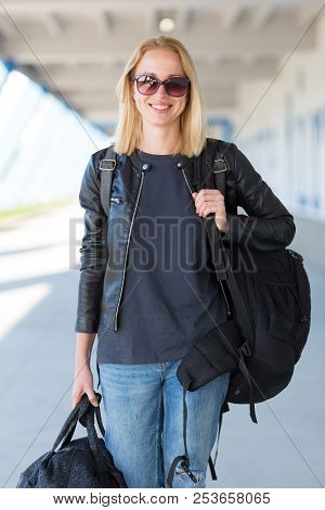 Portrait Of Young Cheerful Female Traveler Wearing Casual Clothes Carrying Heavy Backpack And Luggag