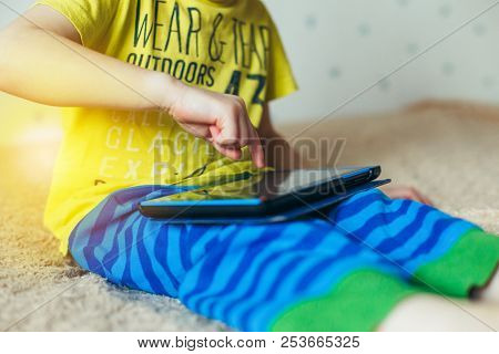 Little Cute Boy In A Green T-shirt Playing Games On A Tablet And Watching Cartoons. Addiction Concep