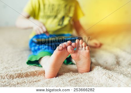 Little Cute Boy In A Green T-shirt Playing Games On A Tablet And