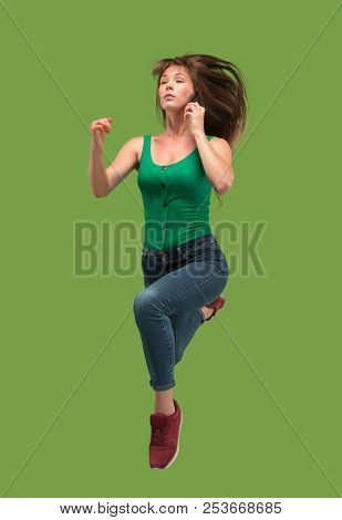 Freedom In Moving. Mid-air Shot Of Pretty Happy Young Woman Jumping And Gesturing Against Orange Stu