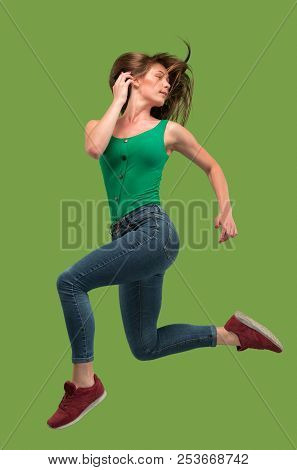 Freedom In Moving. Mid-air Shot Of Pretty Happy Young Woman Jumping And Gesturing Against Orange Stu