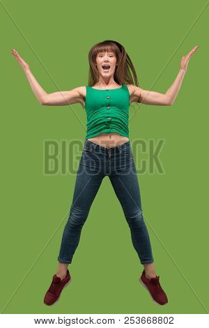 Freedom In Moving. Mid-air Shot Of Pretty Happy Young Woman Jumping And Gesturing Against Orange Stu