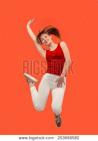 Freedom In Moving. Mid-air Shot Of Pretty Happy Young Woman Jumping And Gesturing Against Orange Stu
