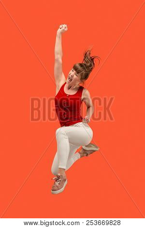 Freedom In Moving. Mid-air Shot Of Pretty Happy Young Woman Jumping And Gesturing Against Orange Stu