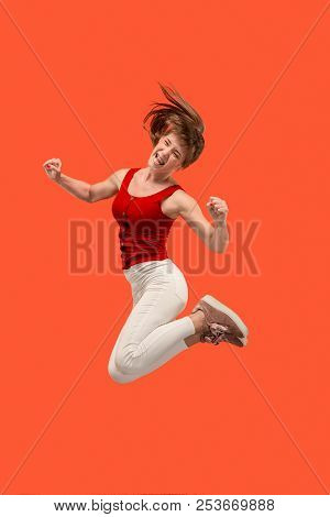 Freedom In Moving. Mid-air Shot Of Pretty Happy Young Woman Jumping And Gesturing Against Orange Stu