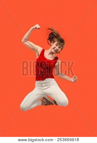 Freedom In Moving. Mid-air Shot Of Pretty Happy Young Woman Jumping And Gesturing Against Orange Stu