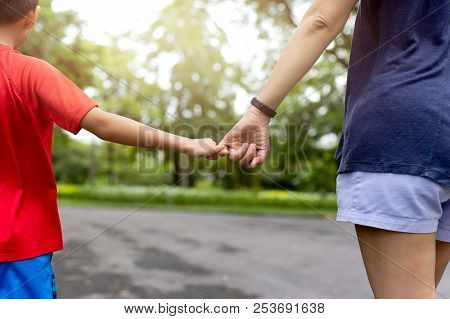 Mother And Son Hooking Up Finger Make Their Promise While Walking In The Park In Summer.