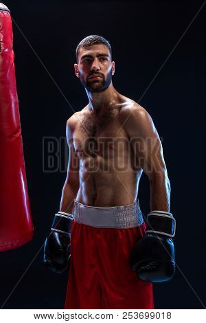 Handsome Athletic Guy In A Red Shorts On A Black Background. The Boxer Is Fetching His Breath After 