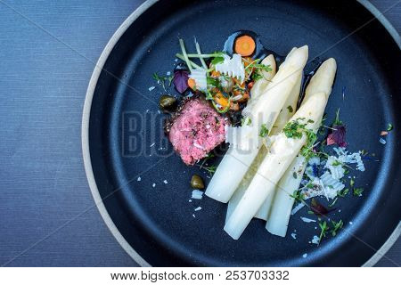 Modern Italian barbecue dry aged tagliata di manzo with white asparagus and parmesan as top view on a plate with copy space left