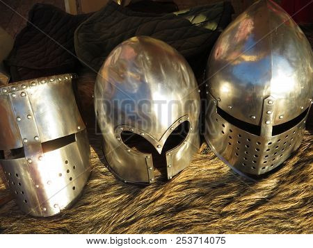 Metal Knightly Helmets On A Bearskin Rug. Armor Of Middle Ages, Medieval Background