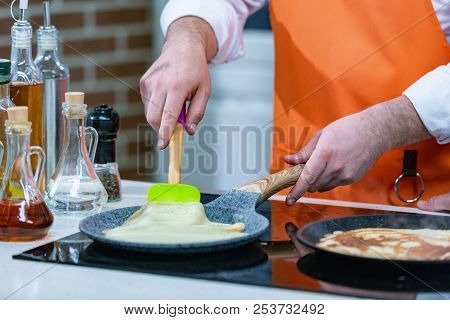 Kitchen Preparation: The Chef Fries Fresh Pancakes In Two Pans