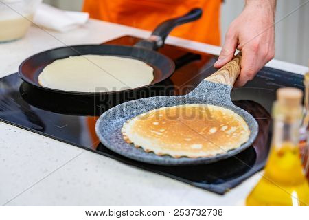 Kitchen Preparation: The Chef Fries Fresh Pancakes In Two Pans