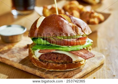 tasty vegan cheeseburger with meatless bacon alternative on rustic wooden table