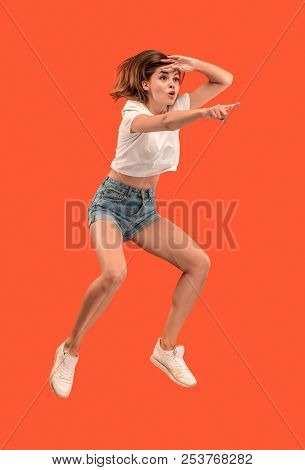 Freedom In Moving. Mid-air Shot Of Pretty Happy Young Woman Jumping And Pointing By Finger Against O