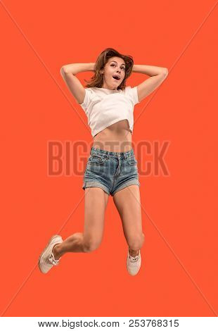 Freedom In Moving. Mid-air Shot Of Pretty Happy Young Woman Jumping And Gesturing Against Orange Stu