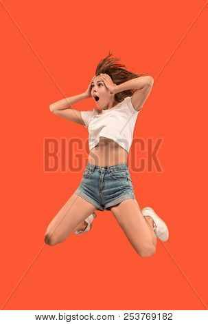Freedom In Moving. Mid-air Shot Of Pretty Happy Young Woman Jumping And Gesturing Against Orange Stu