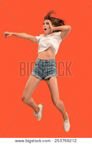 Freedom In Moving. Mid-air Shot Of Pretty Happy Young Woman Jumping And Pointing By Finger Against O