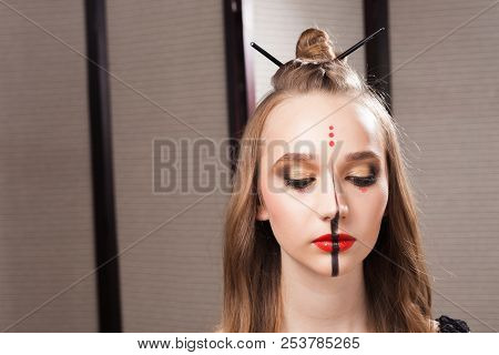 Beautiful Young Serious Model Wearing Professional Unusual Makeup And A Coiffure With Topknot And Br