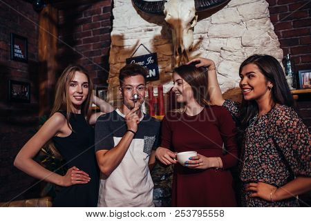 Four Cool Teenagers Wearing Casual Clothes Posing For Camera In A Stylish With Hunting Lodge Interio