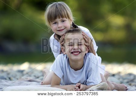 Two Young Happy Cute Blond Smiling Children, Boy And Girl, Brother And Sister Laying Embraced On Peb