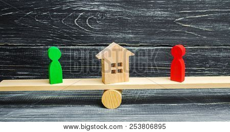 Wooden Figures On The Scales. Clarification Of Ownership Of The House, Real Estate. Court. Rivals In