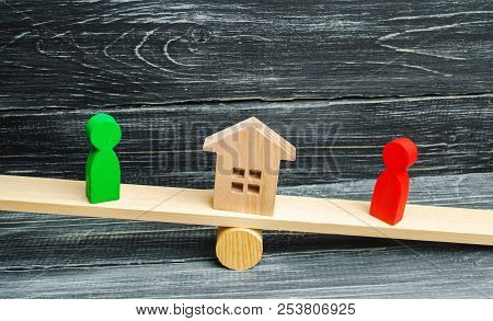Wooden Figures On The Scales. Clarification Of Ownership Of The House, Real Estate. Court. Rivals In