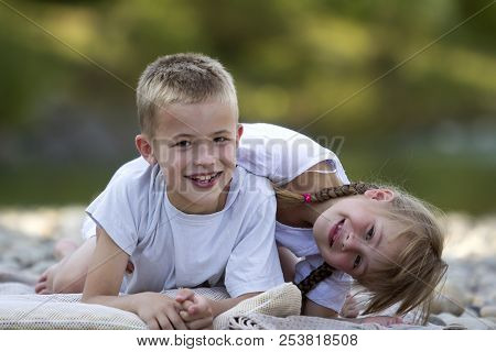 Two Young Happy Cute Blond Smiling Children, Boy And Girl, Brother And Sister Laying Embraced On Peb
