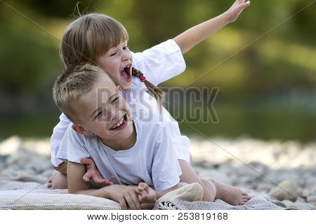 Two Young Happy Cute Blond Laughing Children, Boy And Girl, Brother And Sister Having Fun On Pebbled