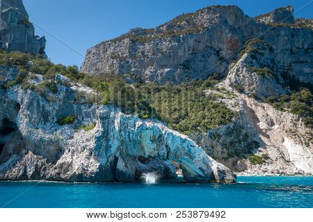 People Jumping Into The Water At Famous Cala Goloritze Beach On The Italian Island Of Sardinia