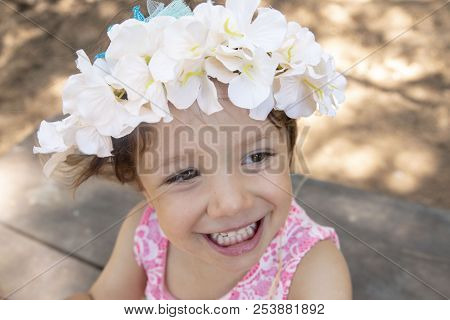 Child Smiling With Flowers On Head Outdoor