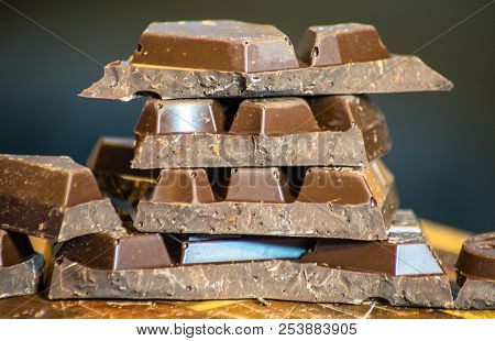 Dark Chocolate Bars Stacked Up With Dark Background In The Ktichen Sitting On Cutting Board
