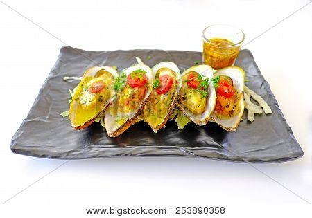 New Zealand Mussels With Dipping Sauce On A Black Plate On A White Background.