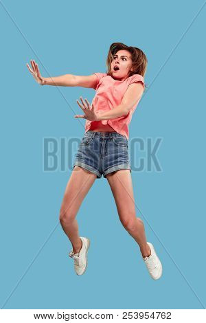 Freedom In Moving. Mid-air Shot Of Pretty Happy Young Woman Jumping And Gesturing Reject Against Blu