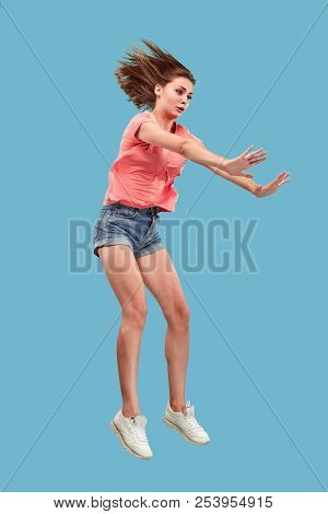 Freedom In Moving. Mid-air Shot Of Pretty Happy Young Woman Jumping And Gesturing Reject Against Blu